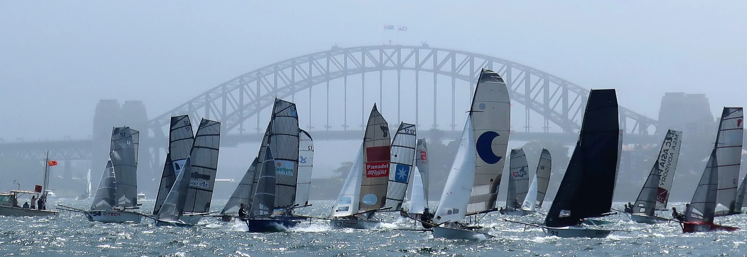 The 12-foot skiff fleet racing on a windy harbour beneath the Sydney Harbour Bridge